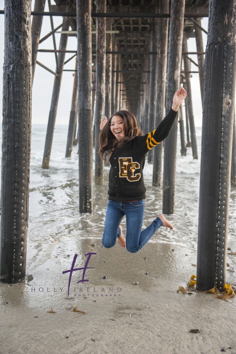 Jumping high school senior photography at the beach at low tide