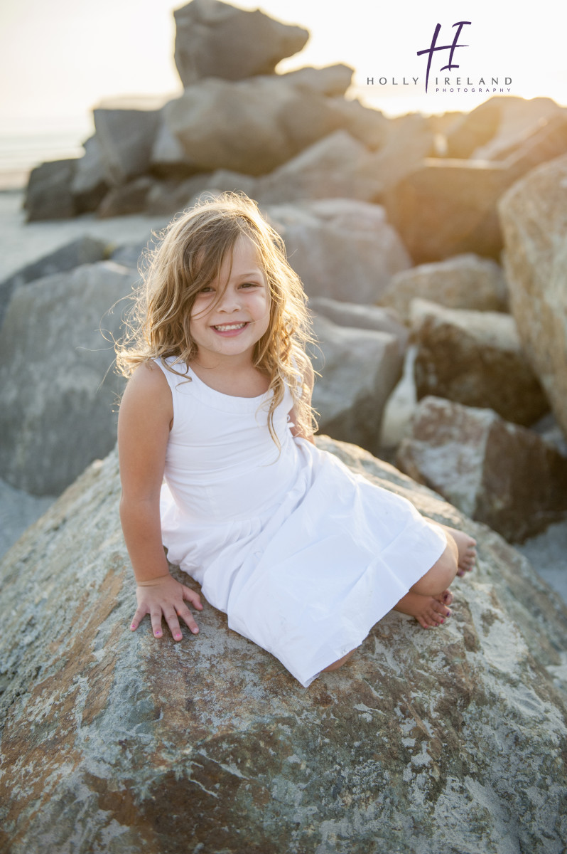 Cute little girl looking like a mermaid on a rock photographed at the beach 